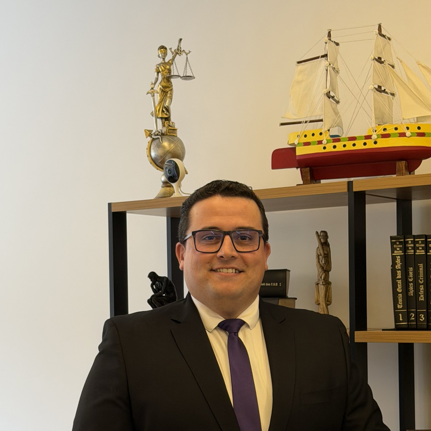 Dr. Sérgio Ruiz em seu escritório de advocacia, junto à estante com estatueta de Têmis